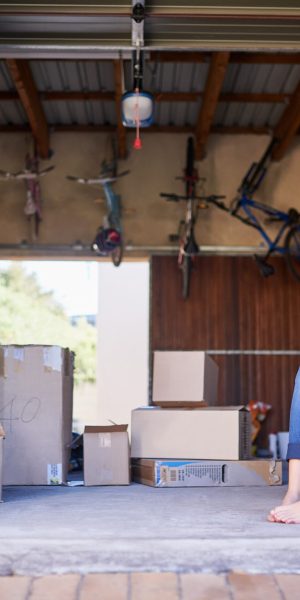 Sitting amongst the storage. Portrait of a young girl sitting on a box in a garage