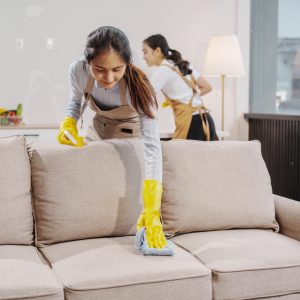 Two women contractors working as housekeepers in an office, wiping glass, sweeping floors, mopping